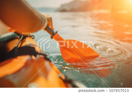Kayak paddle sea vacation. Person paddles with orange paddle oar on kayak in sea. Leisure active lifestyle recreation activity rest tourism travel 107857013