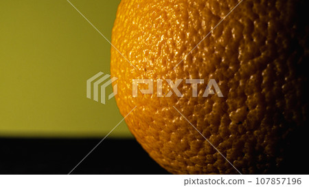 Close up of an orange on a yellow background with copy space. Close up of an orange on a yellow background with copy space. 107857196