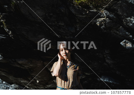 站在山谷岩石懸崖上的年輕女子 107857778