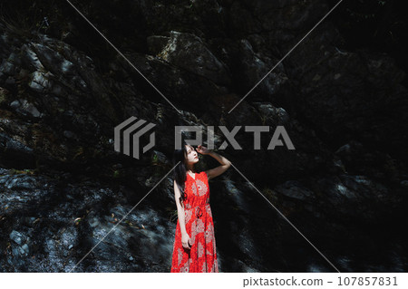 A girl bathed in light in front of a rock 107857831
