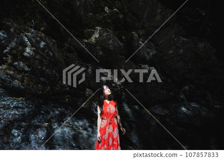 A girl bathed in light in front of a rock 107857833