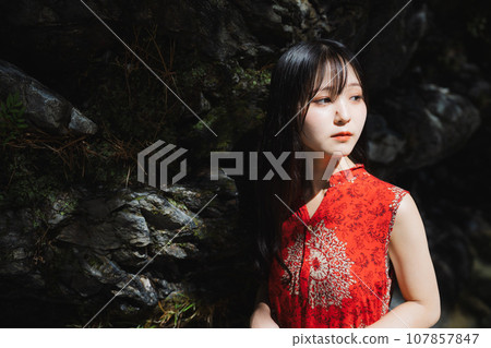 A girl bathed in light in front of a rock 107857847