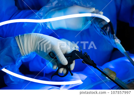 The surgeon's hand operates with a laparoscopic instrument. The surgeon's hand operates with a laparoscopic instrument. 107857997