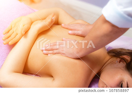 Top view of hands massaging female abdomen.Therapist applying pressure on belly. Woman receiving massage at spa salon 107858897