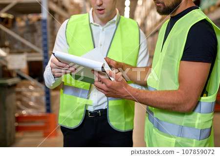 Caucasian two engineers checking goods and supplies on shelves in warehouse. Caucasian two engineers checking goods and supplies on shelves in warehouse. 107859072