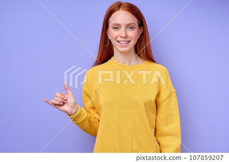 beautiful redhead happy girl, teacher showing letter Y on blue background 107859207