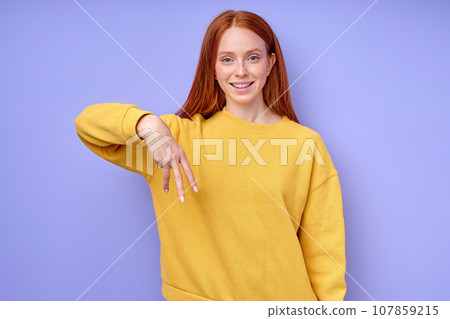 cheerful redhead woman in yellow stylish sweater demonstrating letter W cheerful redhead woman in yellow stylish sweater demonstrating letter W 107859215