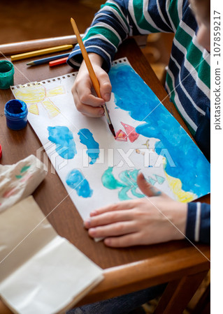 child draws sea and sailboats with paints 107859217