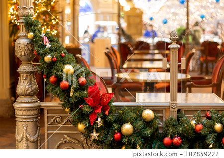 Christmas tree garland on door of cafe, interior with tables 107859222