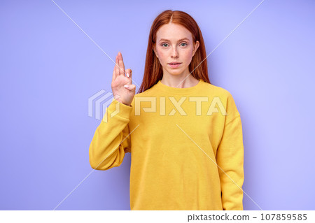 beautiful redhead woman demonstrating the letter F 107859585