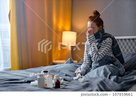 young woman having cough, sneezing, feeling sick and lying on bed, take medicine young woman having cough, sneezing, feeling sick and lying on bed, take medicine 107859661