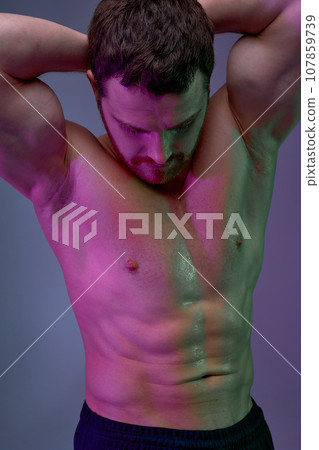 Muscular shirtless sweaty man posing with hands over head, looking down Muscular shirtless sweaty man posing with hands over head, looking down 107859739