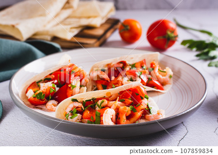 Vegetarian mini tacos with tomatoes, shrimp and herbs on a plate on the table Vegetarian mini tacos with tomatoes, shrimp and herbs on a plate on the table 107859834