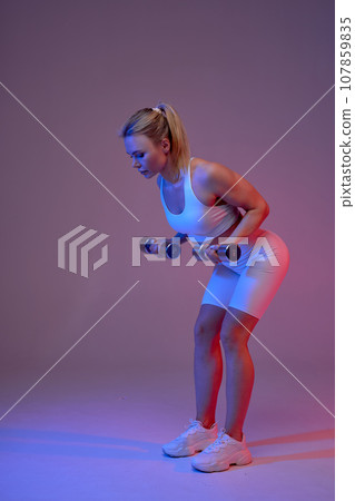 Side view of fit healthy fair-haired girl in sportswear bending and doing exercises Side view of fit healthy fair-haired girl in sportswear bending and doing exercises 107859835