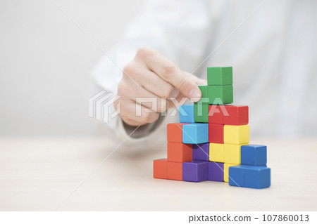 Man's hand stacking colorful wooden blocks. Business development concept 107860013