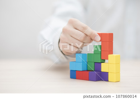 Man's hand stacking colorful wooden blocks. Business development concept Man's hand stacking colorful wooden blocks. Business development concept 107860014
