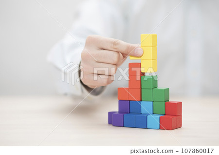 Man's hand stacking colorful wooden blocks. Business development concept 107860017