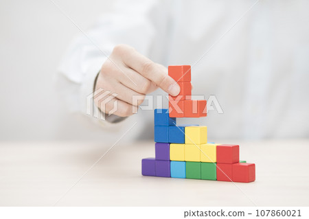 Man's hand stacking colorful wooden blocks. Business development concept 107860021