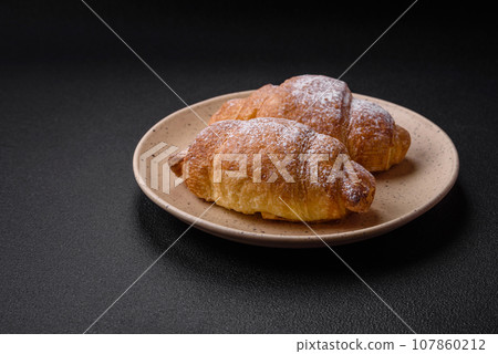 Delicious fresh sweet crispy croissants with chocolate cream on a ceramic plate Delicious fresh sweet crispy croissants with chocolate cream on a ceramic plate 107860212