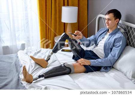 Home entertainments. pleasant handicapped guy with TV controller enjoying movie indoors 107860534