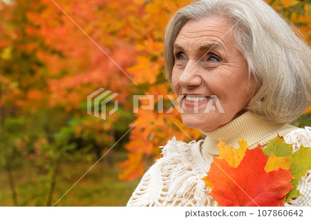 Senior woman walking in the park in autumn. Senior woman walking in the park in autumn. 107860642