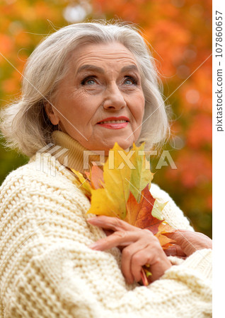 Senior woman walking in the park in autumn. Senior woman walking in the park in autumn. 107860657