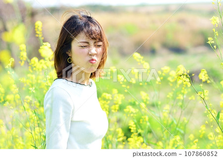 Woman taking a walk in a rape field Woman taking a walk in a rape field 107860852