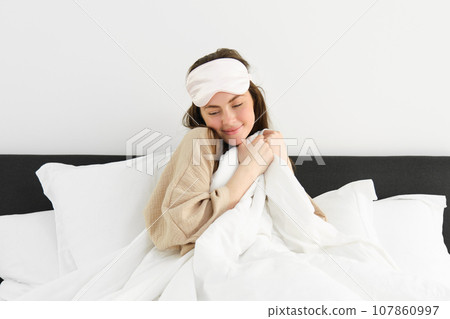 Beautiful woman wakes up in morning, lying in bed and smiling, enjoying her start of the day at home, relaxing in bedroom Beautiful woman wakes up in morning, lying in bed and smiling, enjoying her start of the day at home, relaxing in bedroom 107860997