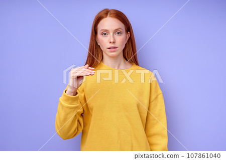 beautiful redhead serious girl, teacher showing letter T on blue background beautiful redhead serious girl, teacher showing letter T on blue background 107861040