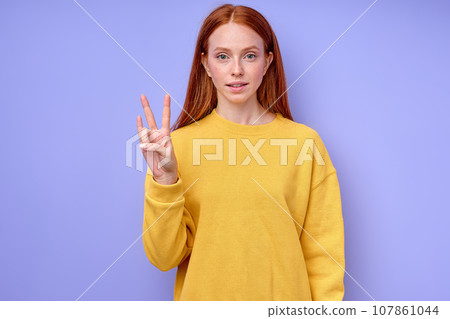 cheerful redhead woman in yellow stylish sweater demonstrating letter N cheerful redhead woman in yellow stylish sweater demonstrating letter N 107861044