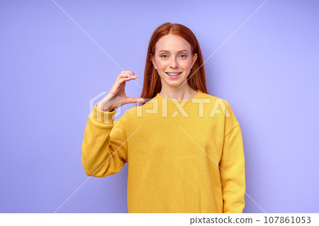 Young smiling red-haired deaf woman wearing yellow sweater showing Young smiling red-haired deaf woman wearing yellow sweater showing 107861053
