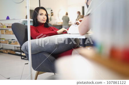 Bored lady client on manicure and pedicure appointment in beauty salon Bored lady client on manicure and pedicure appointment in beauty salon 107861122