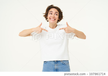 Image of confident, happy young woman, pointing at herself with smiling face, self-assured, standing over white background Image of confident, happy young woman, pointing at herself with smiling face, self-assured, standing over white background 107861714