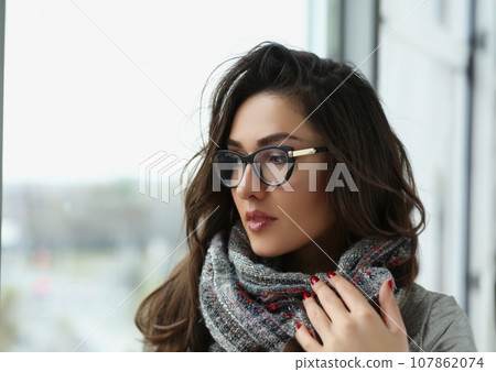 Young beautiful woman in scarf, warming hands, pensive look away, view from window 107862074