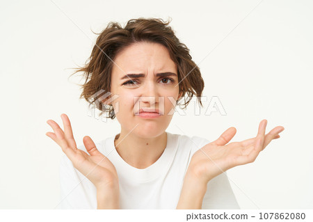 Close up of shocked brunette woman, shrugging and looking disappointed, posing over white studio background 107862080