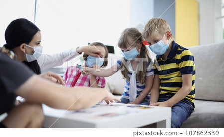 Woman keep checking on kids health, ask to wear face mask, prevent covid spread 107862330
