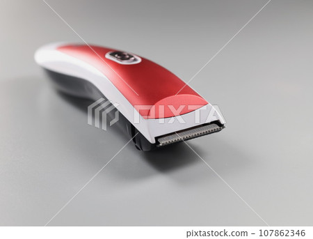 Electric trimming machine for hair, device with red colour design on grey surface Electric trimming machine for hair, device with red colour design on grey surface 107862346