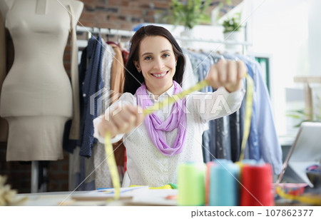 Smiling dressmaker woman willing to tape measure you, find out clothes size 107862377