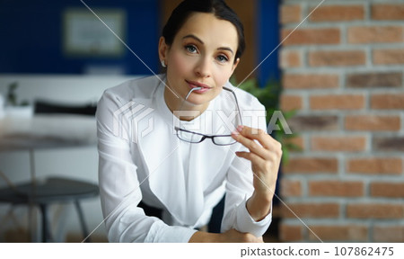 Pretty young lady in office outfit hold black glasses, brunette successful clerk 107862475
