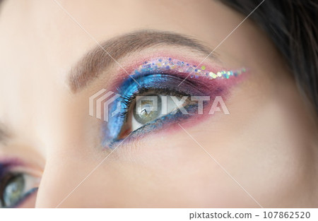 Colourful glitter and eyeshadows, festive bright eye makeup on girls face Colourful glitter and eyeshadows, festive bright eye makeup on girls face 107862520