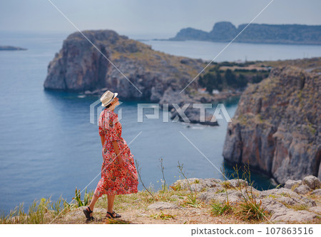 Nice Happy Female Enjoying Sunny Day on Greek Islands. Travel to Greece, Mediterranean islands outside tourist season. Enjoying life and looking at the sea. Turquoise sea background. 107863516