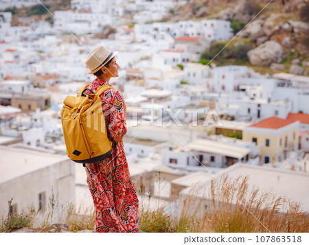 Nice Happy Female Enjoying Greek Islands. Travel to Greece, Mediterranean islands outside tourist season. Having fun at stunning view on sea resort and old town of Lindos on mountain 107863518
