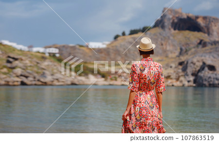 Nice Happy Female Enjoying Greek Islands. Travel to Greece, Mediterranean islands outside tourist season. Having fun at stunning view on sea resort and old town of Lindos on mountain 107863519