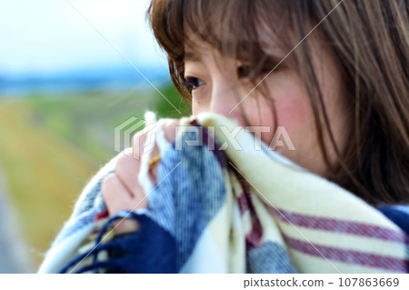 A woman wearing a scarf looking cold in a winter park 107863669