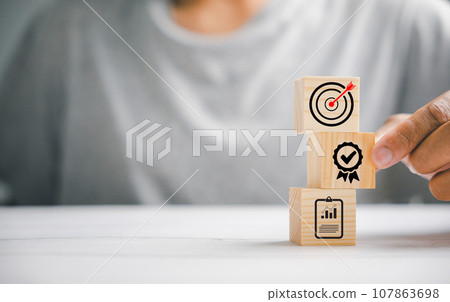 Hand skillfully arranging wooden blocks to form a structured stack, highlighting the importance of a business strategy and action plan. Targeting business goals and development. Hand skillfully arranging wooden blocks to form a structured stack, highlighting the importance of a business strategy and action plan. Targeting business goals and development. 107863698