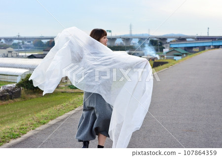 A woman feeling the wind with a veil A woman feeling the wind with a veil 107864359