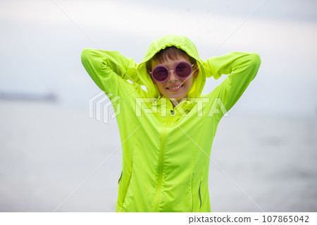 A handsome boy in a bright green sweater and purple sunglasses. Portrait of a happy boy on holiday or vacation. 107865042