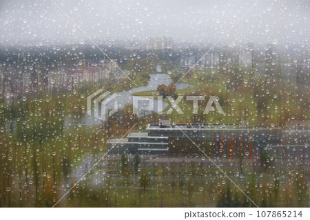 Behind the glass covered with autumn raindrops is a landscape of a gray and boring city. 107865214