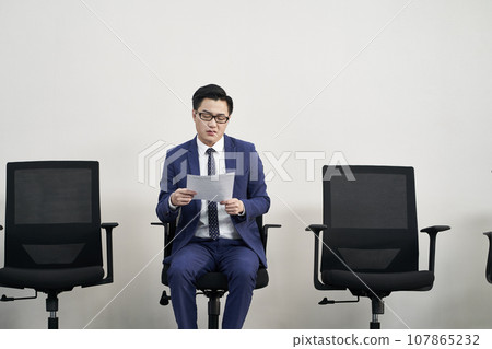 frustrated asian business man sitting in a chair 107865232