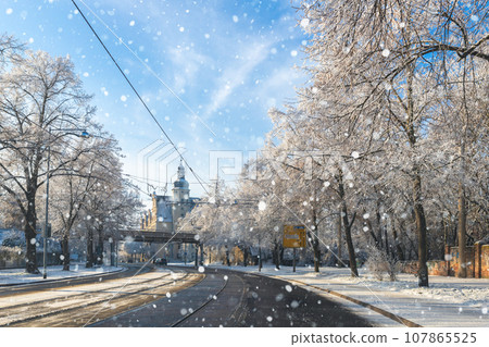Scenic view of Halberstadter street road tram rails in Magdeburg old city center against blue sky on cold frosty winter day. Snowy sunny german cityscape cold weather. European travel destination Scenic view of Halberstadter street road tram rails in Magdeburg old city center against blue sky on cold frosty winter day. Snowy sunny german cityscape cold weather. European travel destination 107865525